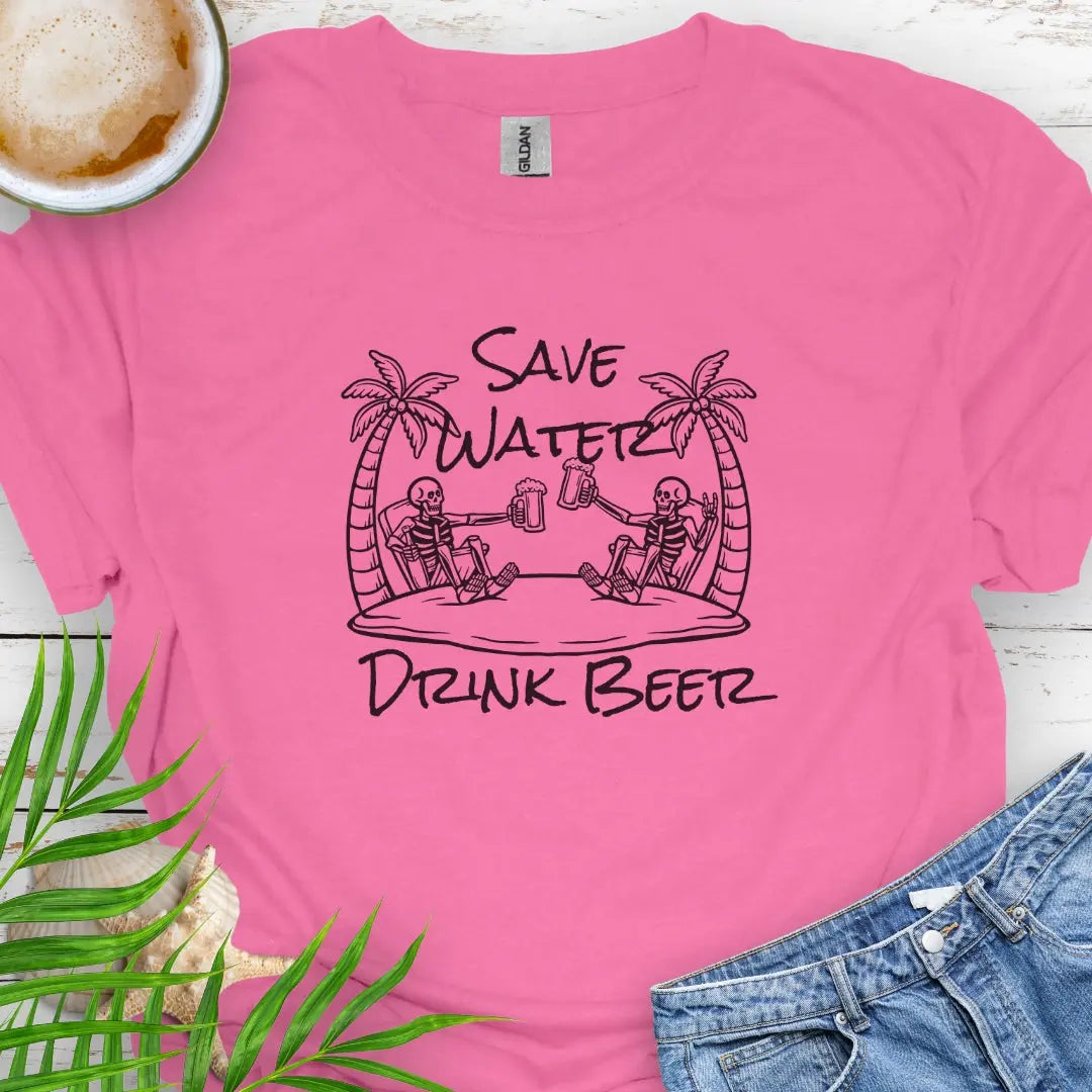 Azalea T-shirt featuring two skeletons on a beach clinking beer bottles with the phrase "Save Water Drink Beer" in a playful coastal setting.