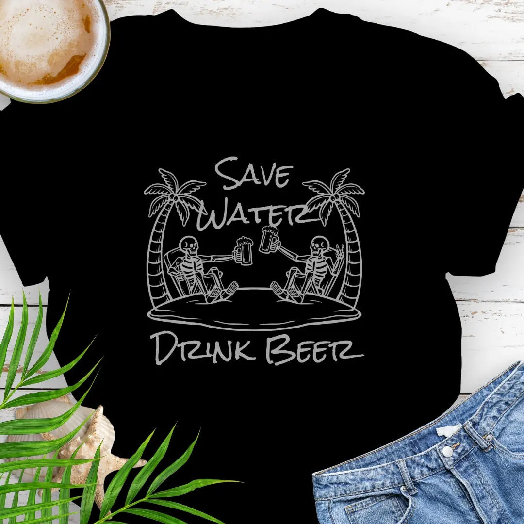 Black T-shirt featuring two skeletons on a beach clinking beer bottles with the phrase "Save Water Drink Beer" in a playful coastal setting.