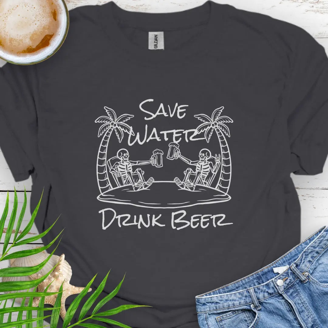 Charcoal T-shirt featuring two skeletons on a beach clinking beer bottles with the phrase "Save Water Drink Beer" in a playful coastal setting.
