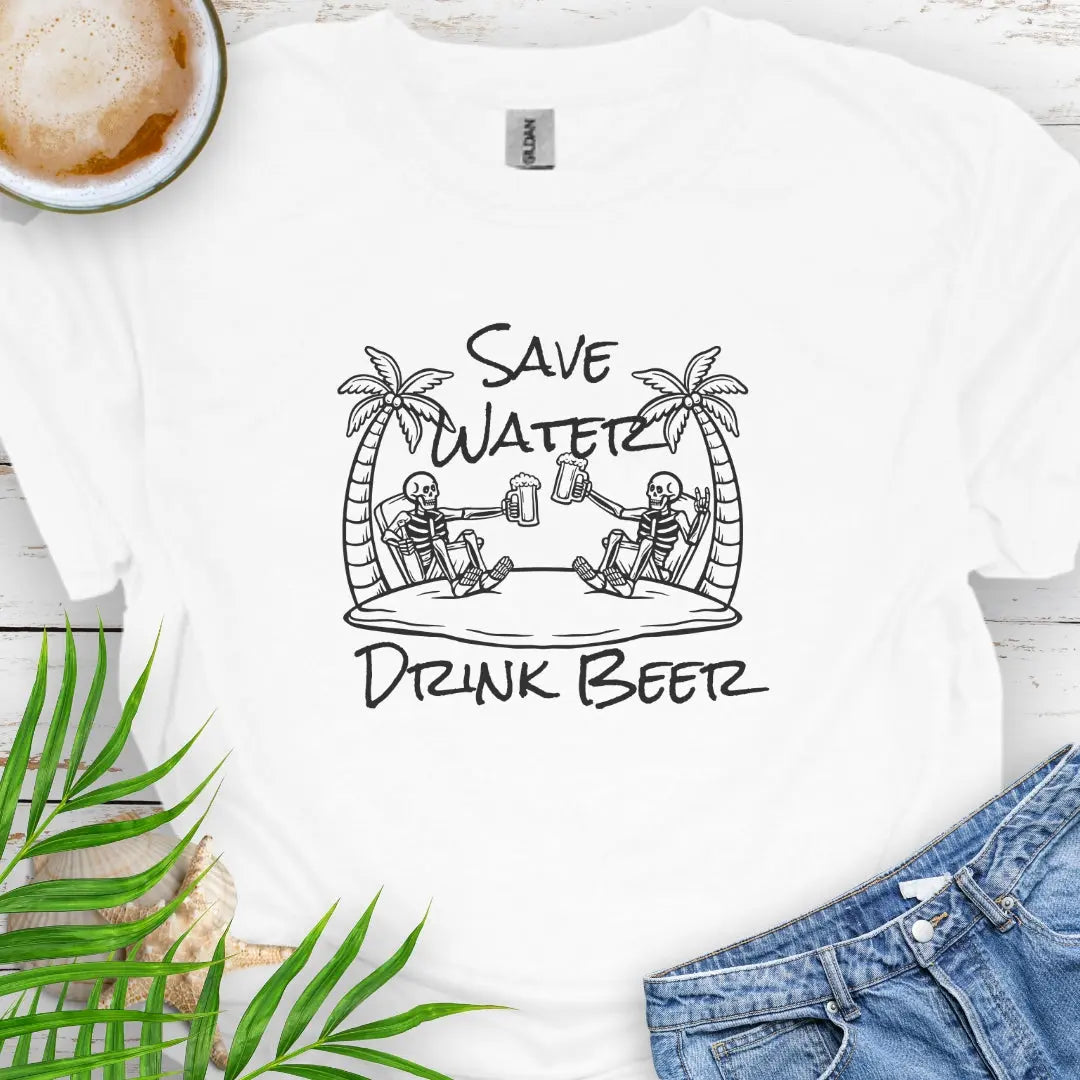 White T-shirt featuring two skeletons on a beach clinking beer bottles with the phrase "Save Water Drink Beer" in a playful coastal setting.