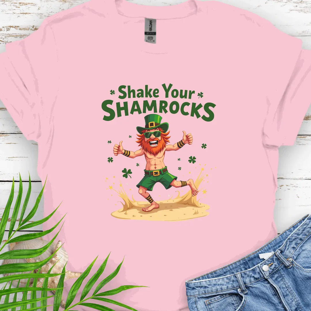 Shop our fun and festive dancing leprechaun in beach attire with shamrock confetti with the text 'Shake Your Shamrocks' Light Pink T-shirt! Perfect for St. Patrick's Day celebrations or anyone who loves a touch of whimsy in their wardrobe.