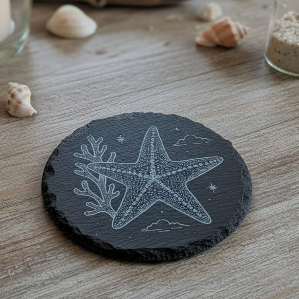 Black slate coaster with a white starfish design engraved.