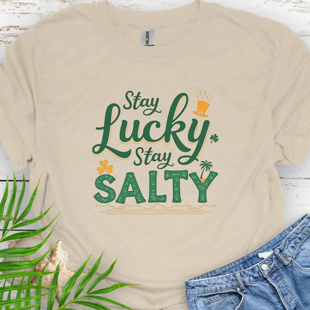 Our Stay Lucky Stay Salty Natural T-shirt with St. Patrick's Day and beach embellishments including shamrock, leprechaun hat, palm tree and ocean waves.