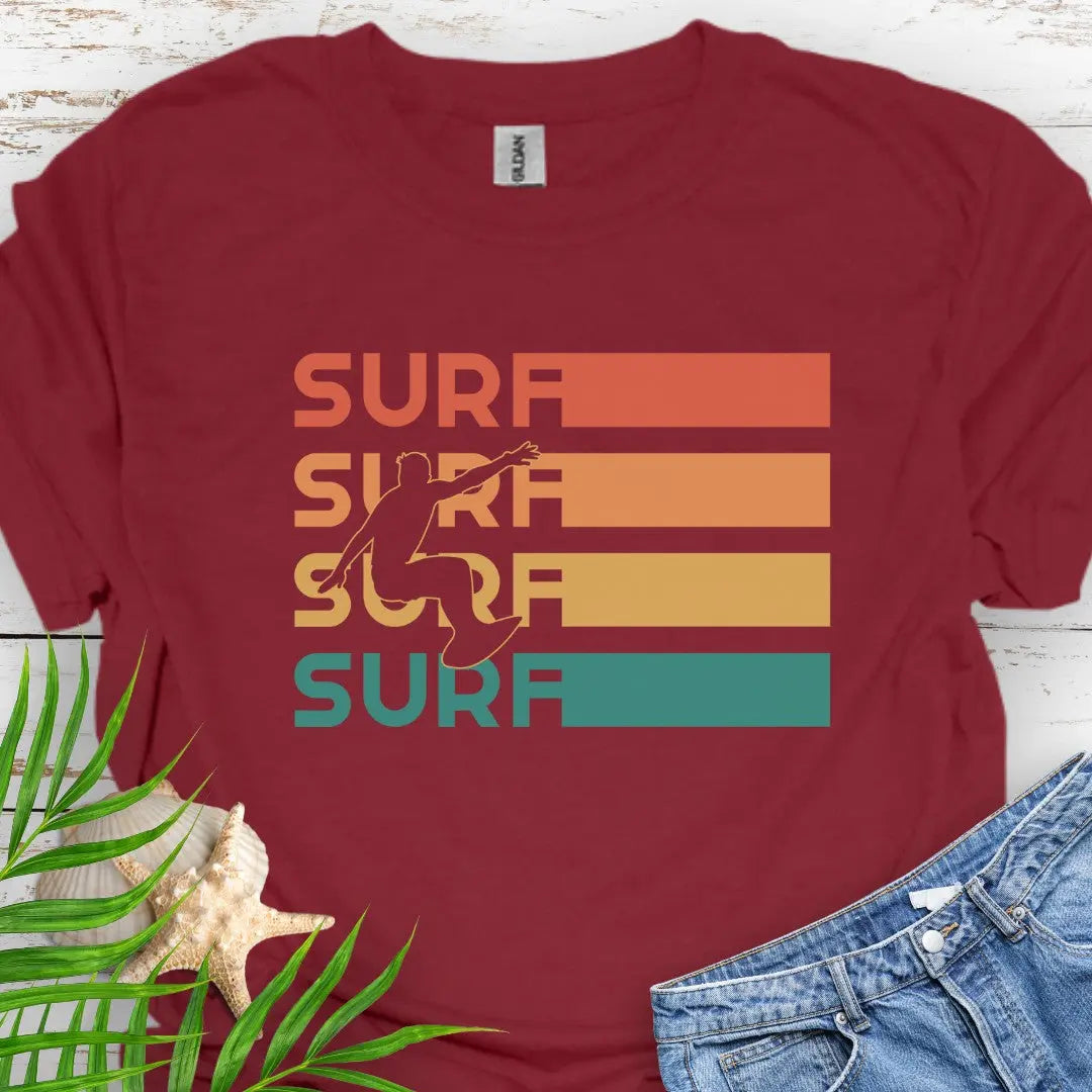 Cardinal Red T-shirt with silhouette of surfer over four rows that says surf in rainbow colors and extend out in rectangle. Perfect for surfing enthusiasts.