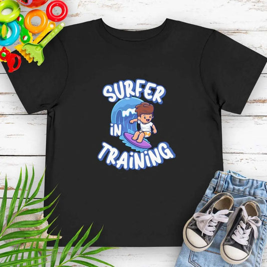 Surfer in Training Toddler's Black T-shirt featuring a child surfing.