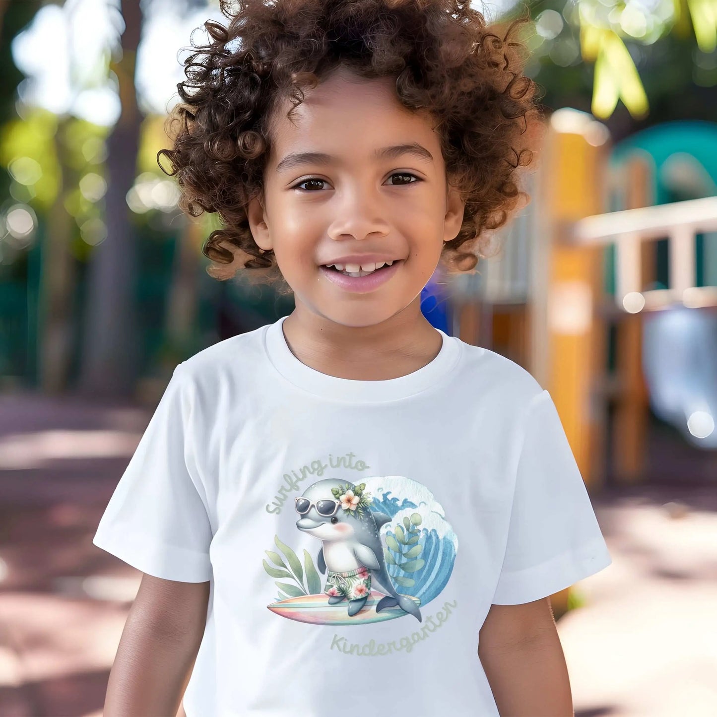 A boy wearing our Surfing Into Kindergarten White Toddler's T-shirt with a fun dolphin surfing.