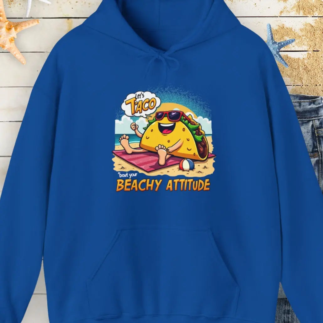 Royal Blue hoodie with a taco wearing sunglasses laying on a beach towel on the beach with the text Let's Taco 'bout your Beachy Attitude.
