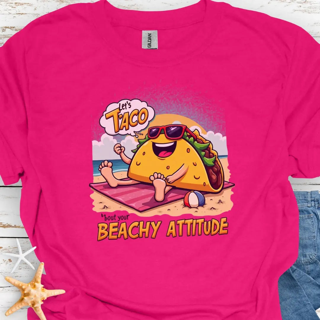 Heliconia t-shirt with a taco wearing sunglasses laying on a beach towel on the beach with the text Let's Taco 'bout your Beachy Attitude.