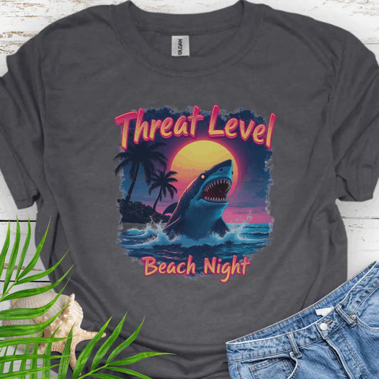 Dark Heather T-shirt with the words Threat Level Beach Night and a shark coming out of the ocean with a bright moon background in a retro 80's movie poster vibe.