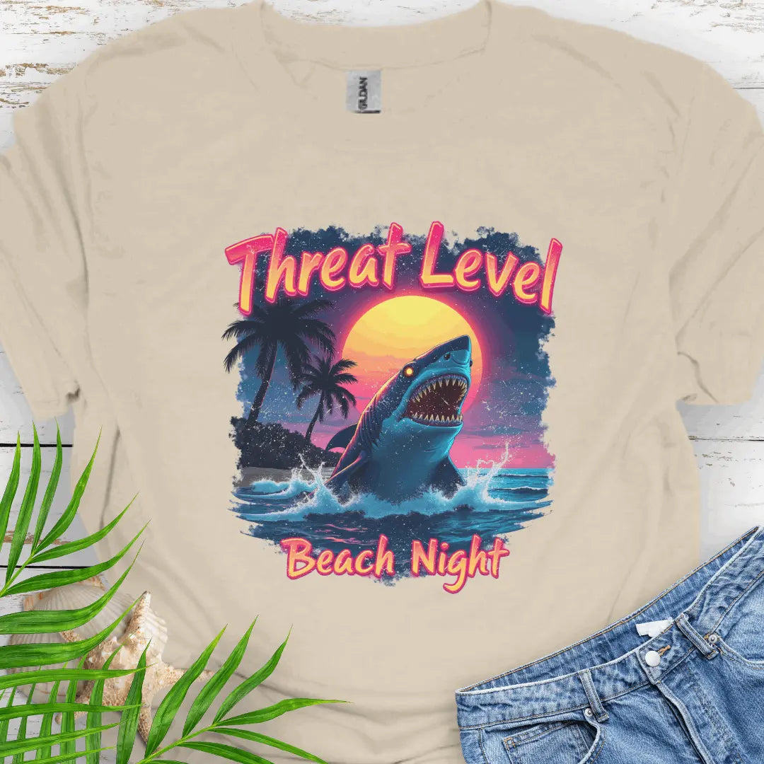 Natural T-shirt with the words Threat Level Beach Night and a shark coming out of the ocean with a bright moon background in a retro 80's movie poster vibe.