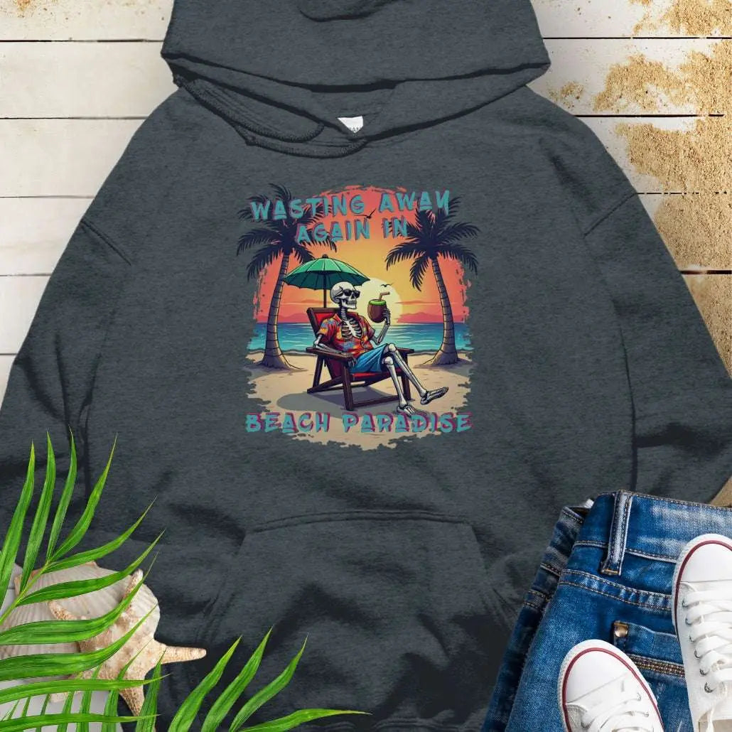A Dark Heather Hoodie with a skeleton in a Hawaiian Shirt sitting under a beach umbrella on the beach at sunset with a coconut drink between two palm trees that says Wasting Away in Beach Paradise.