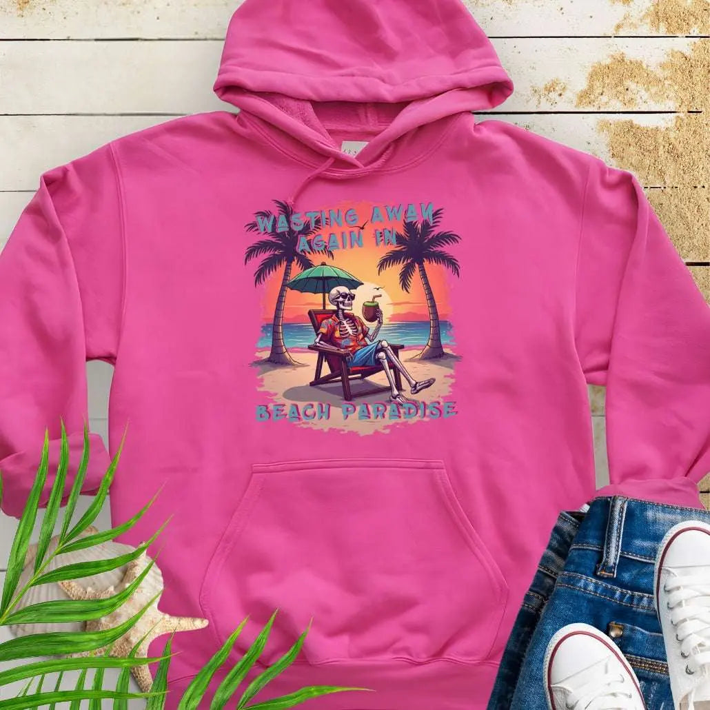 A Heliconia Hoodie with a skeleton in a Hawaiian Shirt sitting under a beach umbrella on the beach at sunset with a coconut drink between two palm trees that says Wasting Away in Beach Paradise.