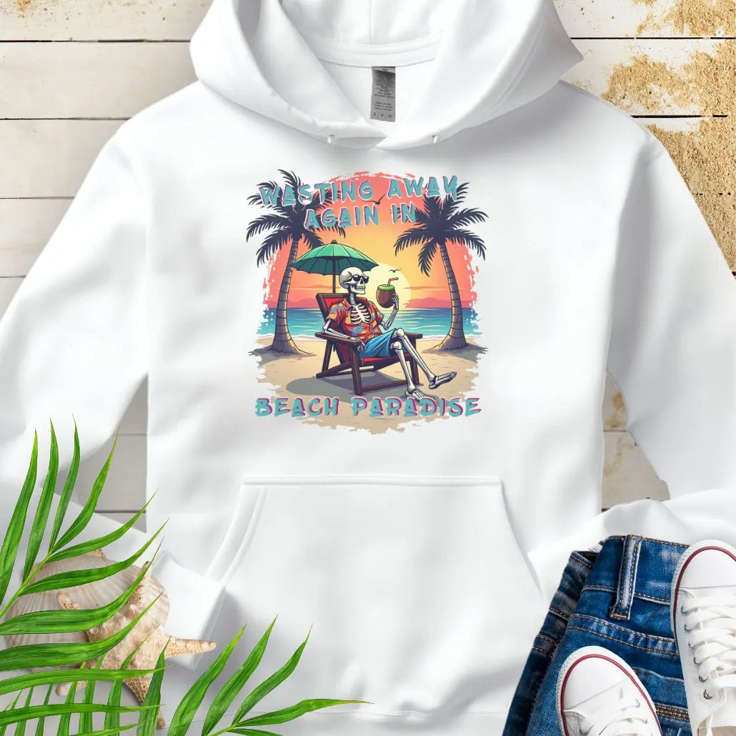 A White Hoodie with a skeleton in a Hawaiian Shirt sitting under a beach umbrella on the beach at sunset with a coconut drink between two palm trees that says Wasting Away in Beach Paradise.