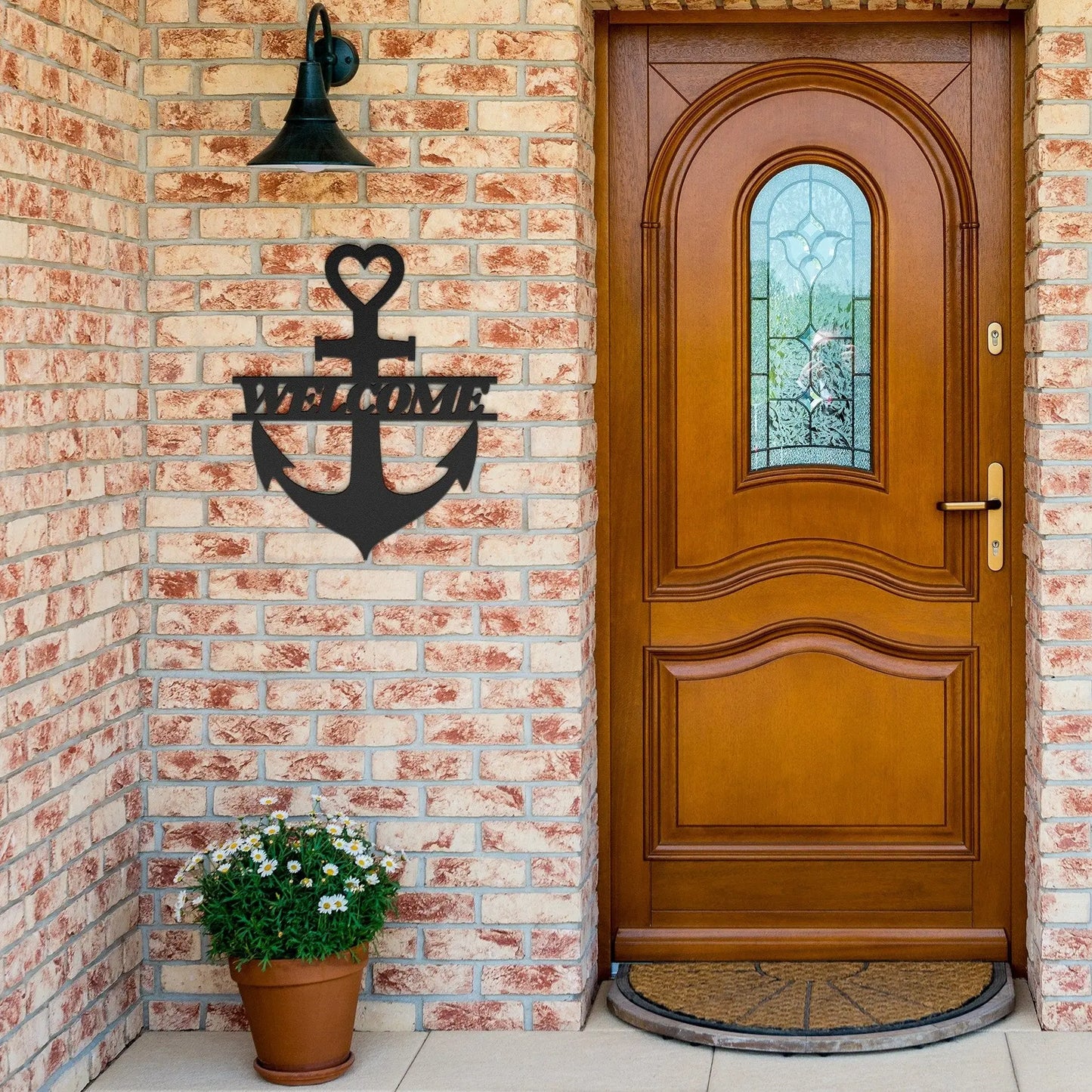 Black metal wall art shaped like an anchor with a heart at the top and the word “Welcome” cut out in the center; made of powder-coated steel hanging near the front door.