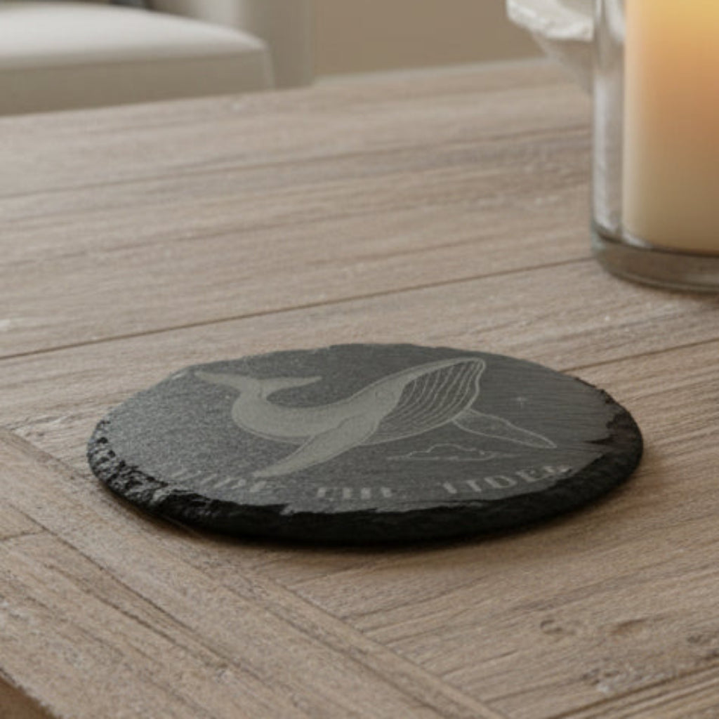 Black slate coaster engraved with whale design with text Ride the Tides.