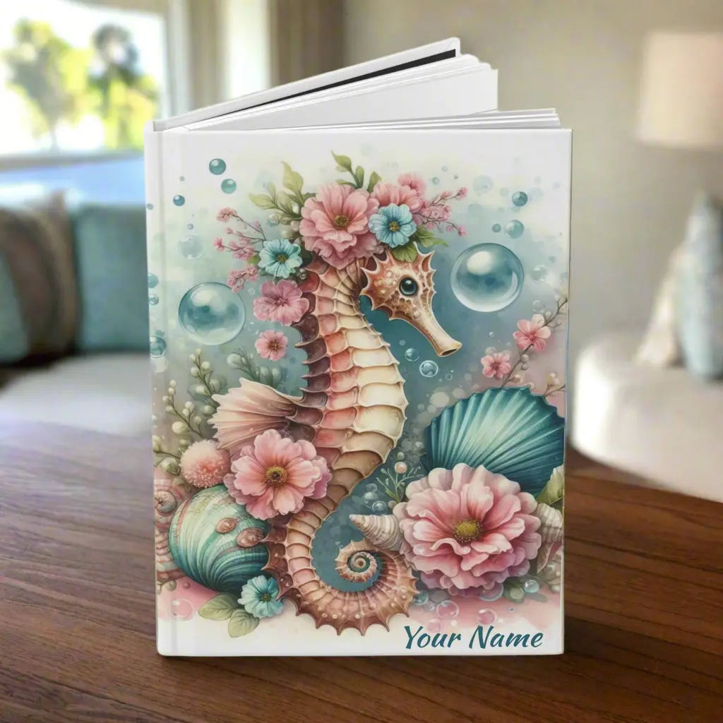 Our hardcover journal brings a touch of ocean magic with a beautifully designed seahorse surrounded by soft, dreamy aqua and pink flowers, bubbles and shells. Perfect for journaling, sketching, or organizing your thoughts, it’s both stylish and durable.