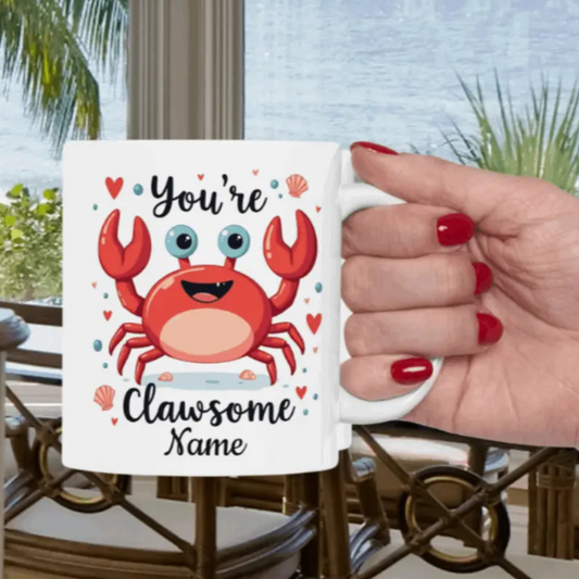 White 11 oz ceramic mug with happy crab with text You're Clawsome personalized with recipient name. Ideal for crab lovers, personalized gift seekers, and those looking to add some fun to their daily beverage enjoyment.
