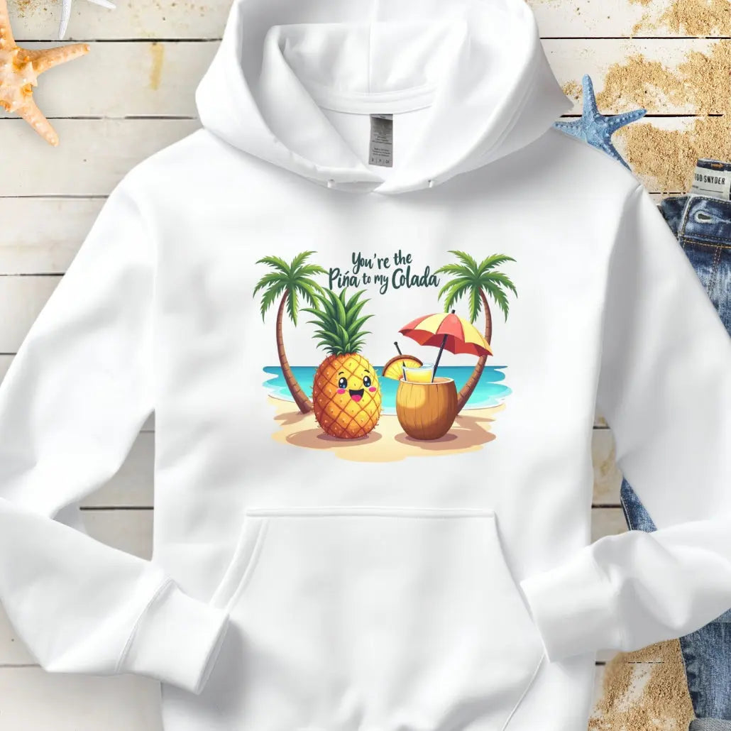 White Hoodie with a pineapple and a coconut pina colada on a beach between two palm trees with the text You're the Pina to my Colada.