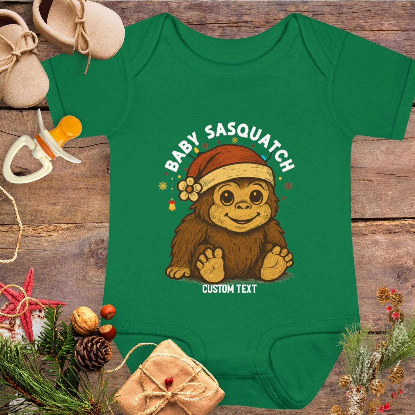 Green baby onesie with a cartoon Sasquatch wearing a Santa hat and custom text.