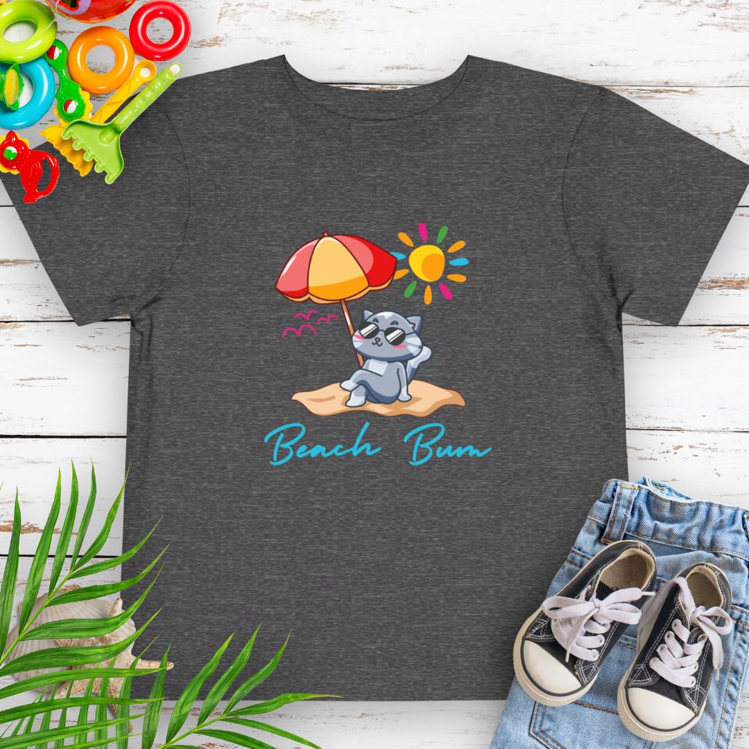 Dark Heather Grey Beach Bum toddler t-shirt with vibrant playful summer design of a cute cat wearing sunglasses laying on the beach under an umbrella.