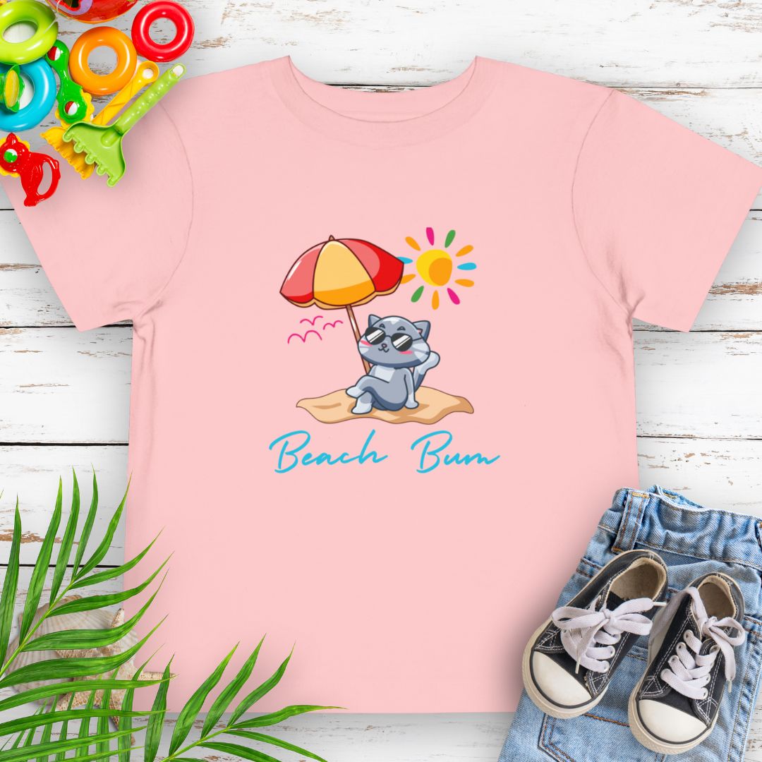 Pink Beach Bum toddler t-shirt with vibrant playful summer design of a cute cat wearing sunglasses laying on the beach under an umbrella.
