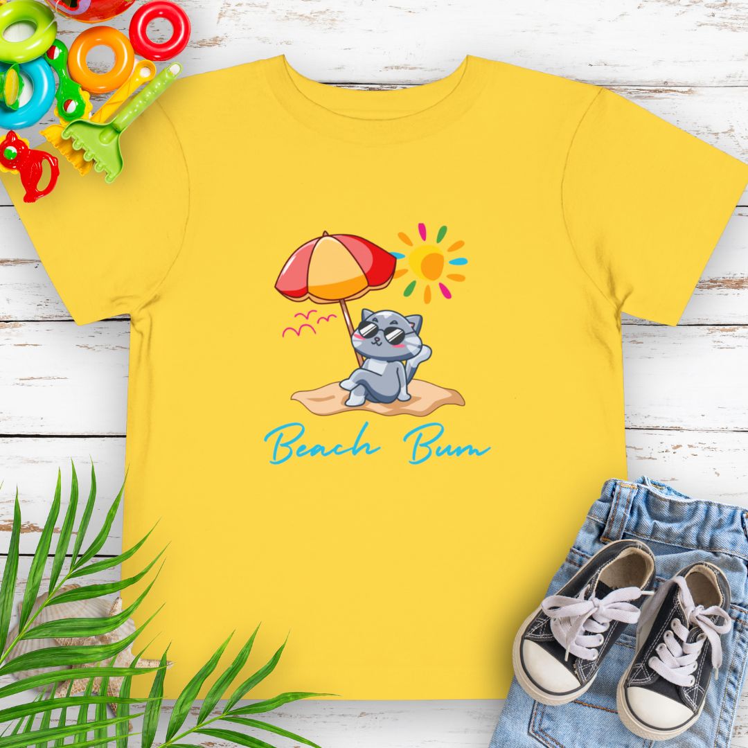 Yellow Beach Bum toddler t-shirt with vibrant playful summer design of a cute cat wearing sunglasses laying on the beach under an umbrella with text Beach Bum.