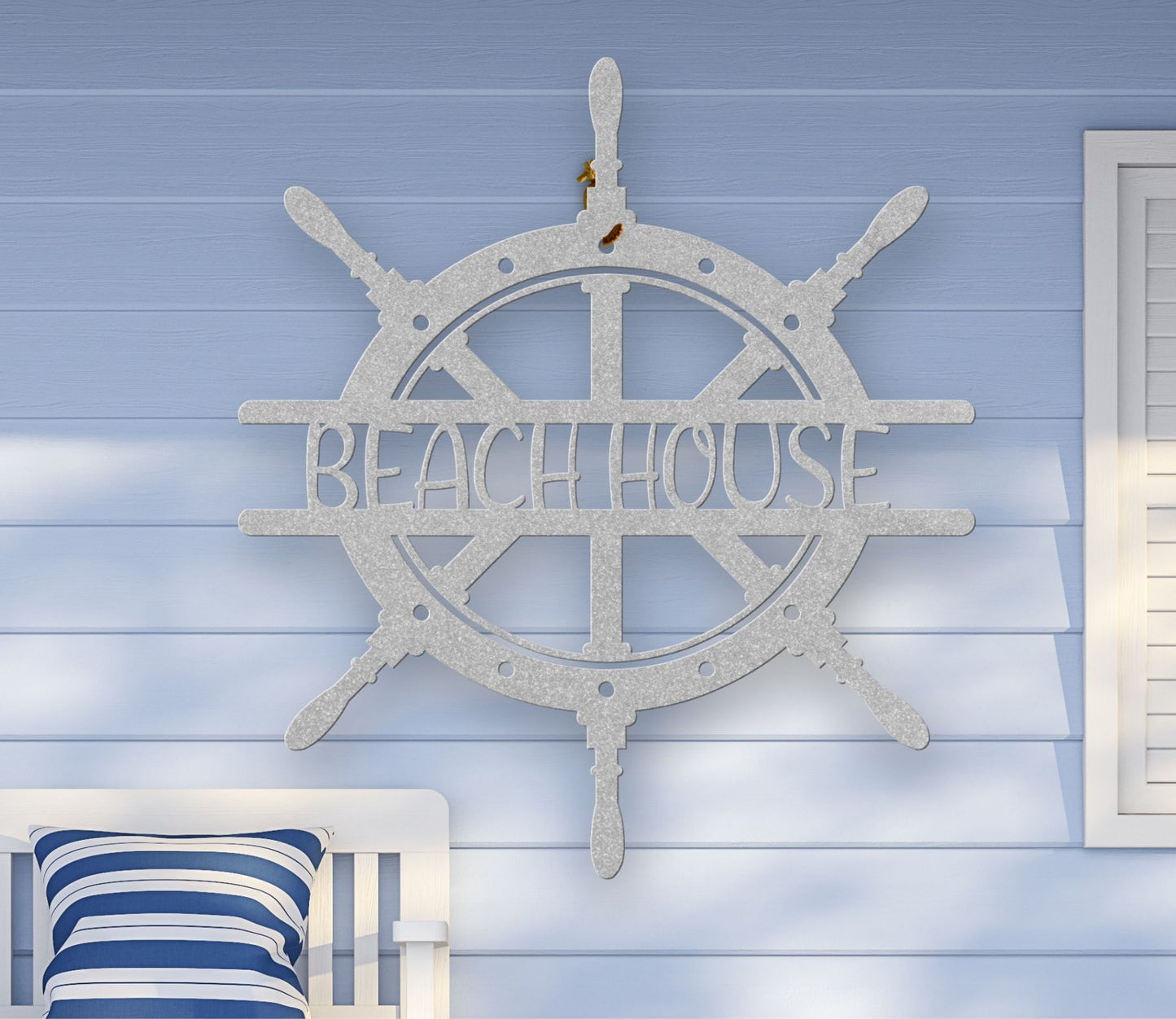 Silver metal wall art shaped like a ship wheel with the words “Beach House” cut out in the center, available in multiple colors and sizes.