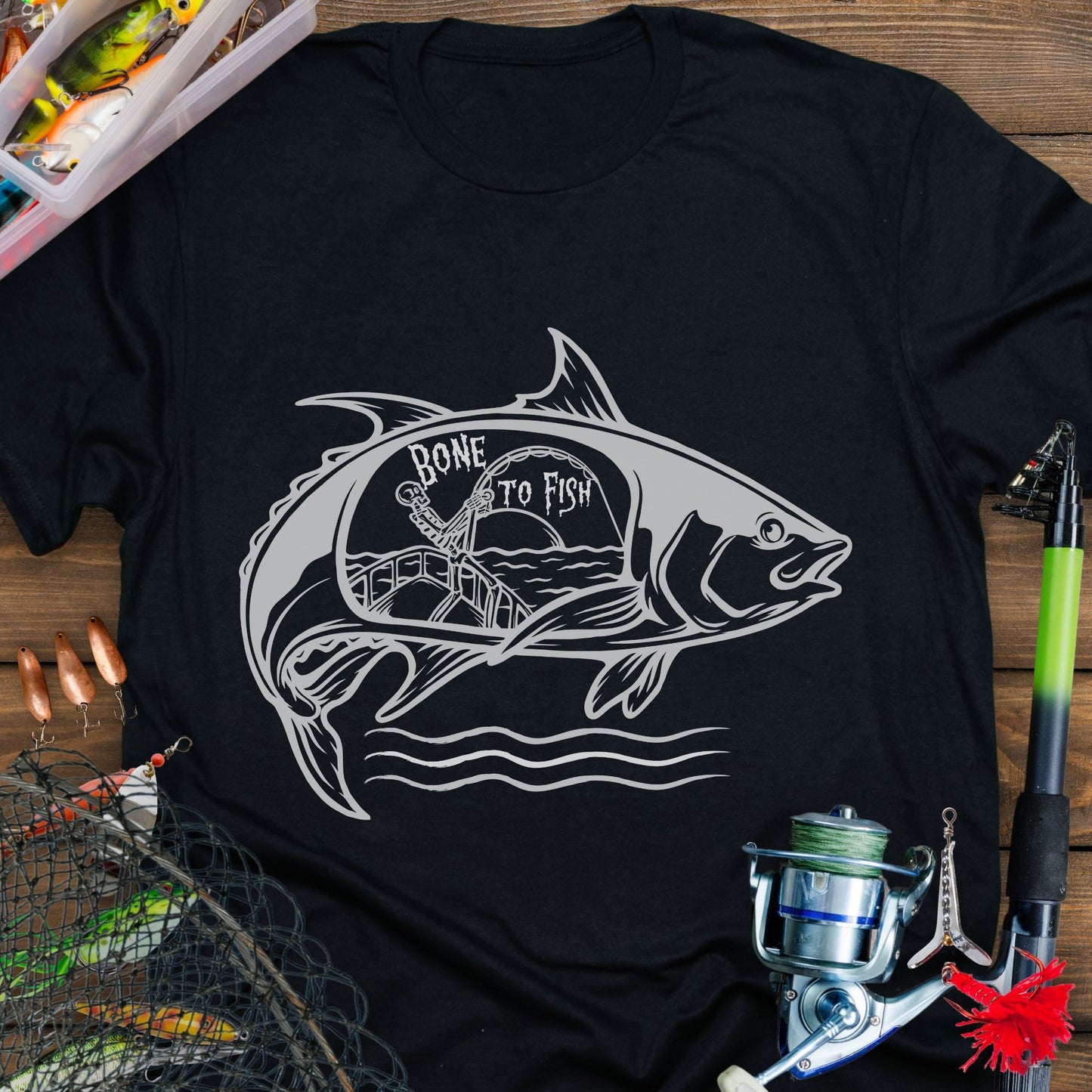 Black T-shirt with “Bone for Fishing” text inside a large fish silhouette containing a skeleton fishing off a boat, gothic nautical design for anglers.