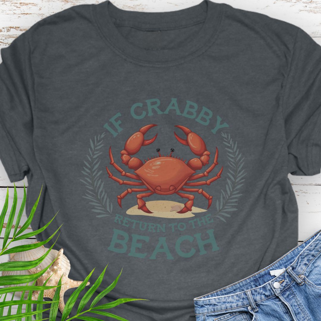 Gray t-shirt with a crab graphic and text 'If Crabby Return to the Beach' on a wooden surface with leaves and jeans.