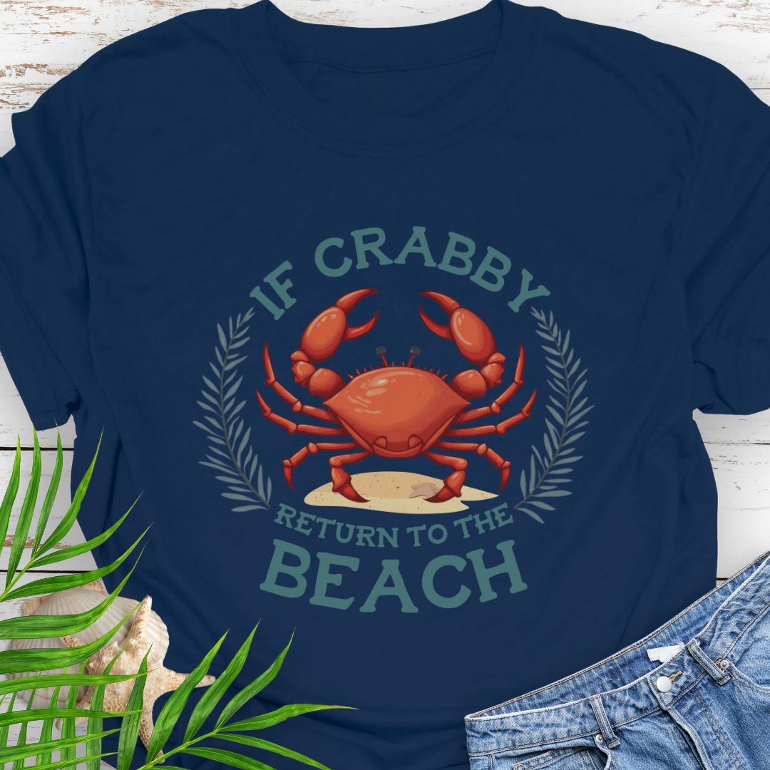 Navy blue t-shirt with a red crab graphic and text 'If Crabby Return to the Beach' on a wooden surface with leaves and jeans.