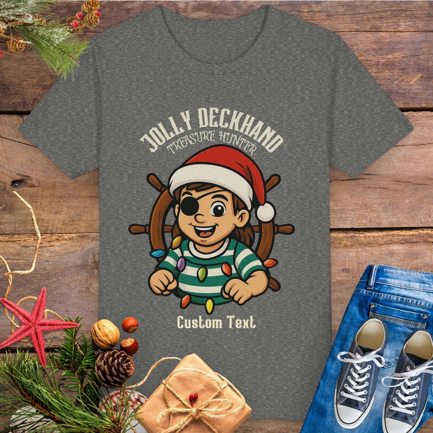 Gray t-shirt with a Christmas-themed design of a girl on a ship's wheel, surrounded by festive items and text 'Jolly Deckhand Treasure Hunter' that can be personalized.