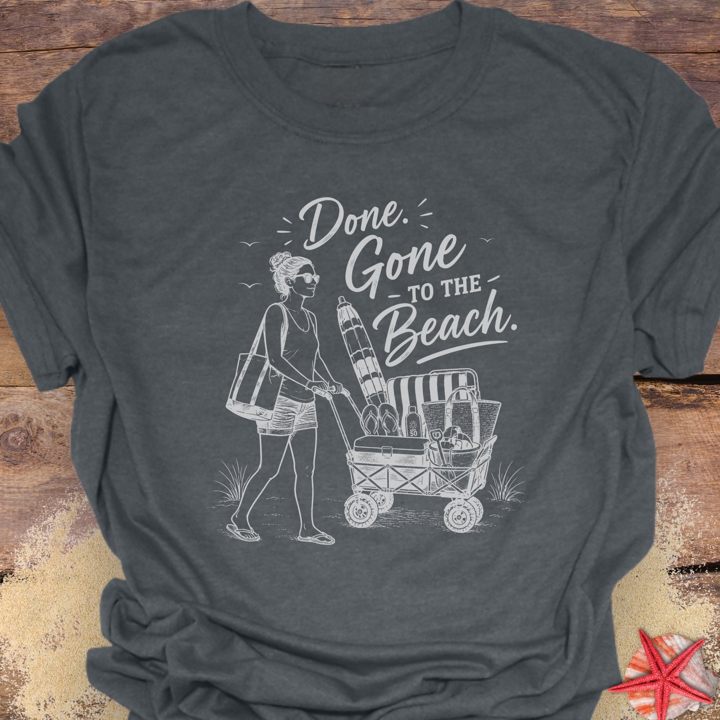 Dark Heather Gray unisex t-shirt with a woman pushing a cart of beach equipment and text "Done. Gone to the Beach."