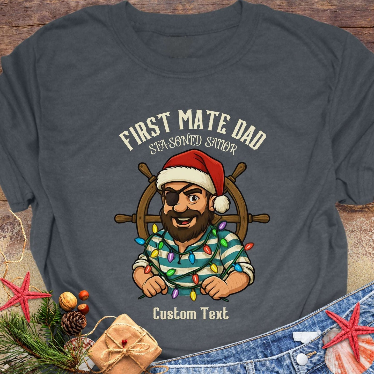 Gray t-shirt with a cartoon pirate wearing a Santa hat and 'First Mate Dad' text on a wooden surface.