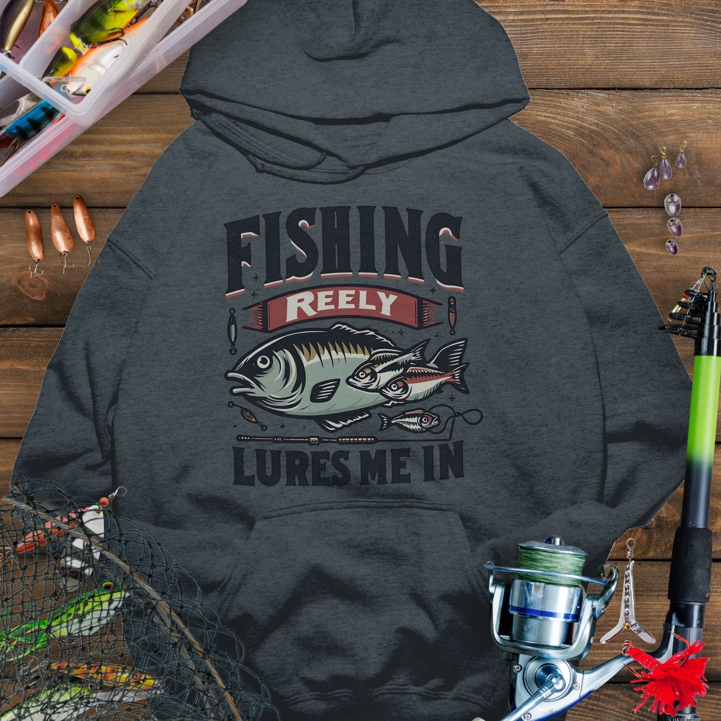 Dark Gray fishing hoodie with fish and tackle graphics and the phrase “Fishing Reely Lures Me In”.