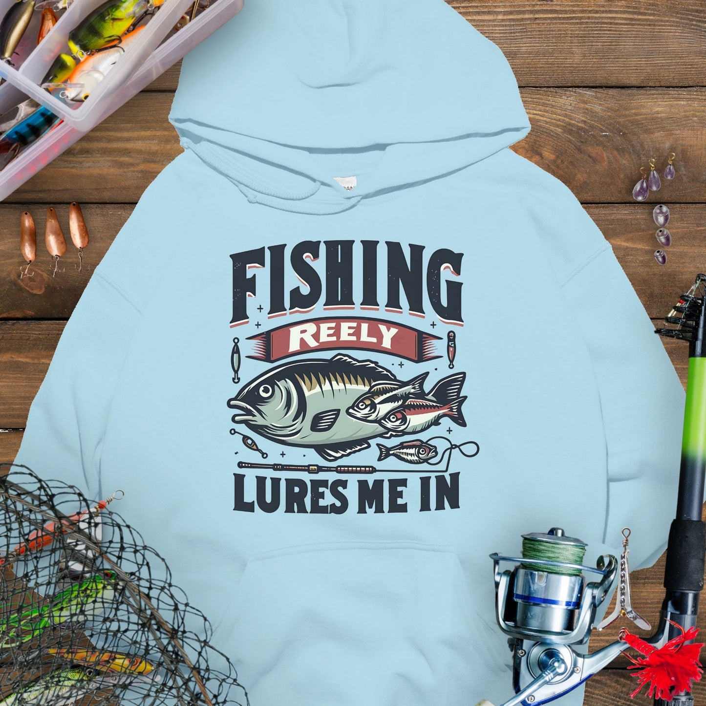 Light Blue fishing hoodie with fish and tackle graphics and the phrase “Fishing Reely Lures Me In”.