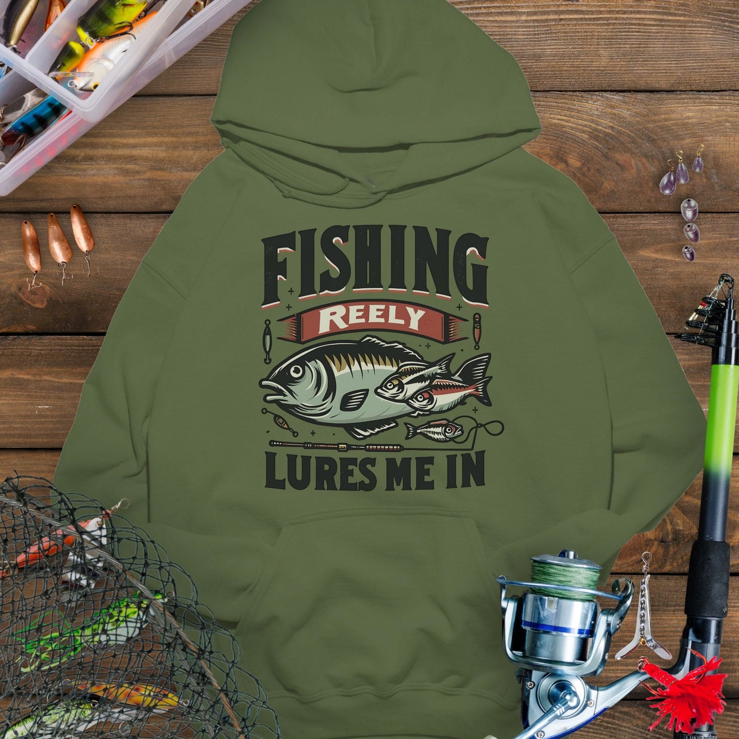 Military Green fishing hoodie with fish and tackle graphics and the phrase “Fishing Reely Lures Me In”.