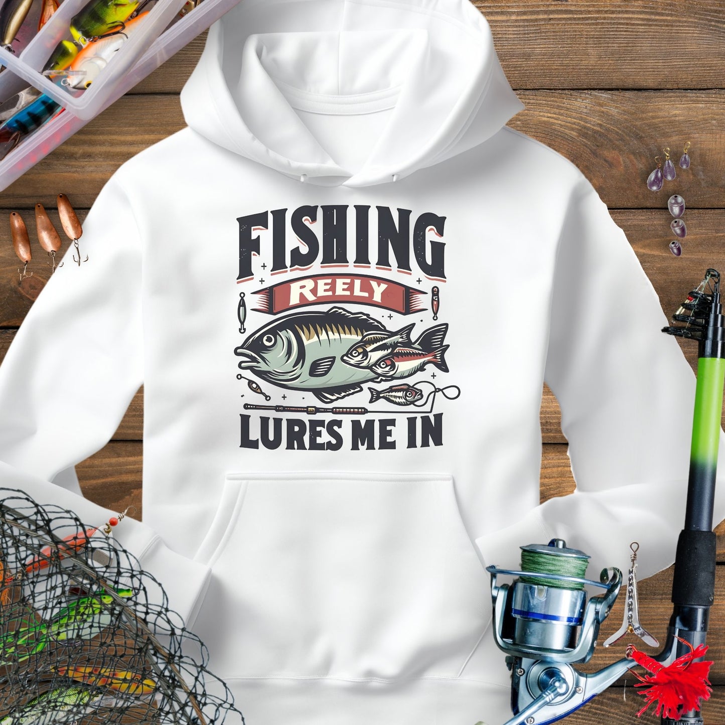 White fishing hoodie with fish and tackle graphics and the phrase “Fishing Reely Lures Me In”.