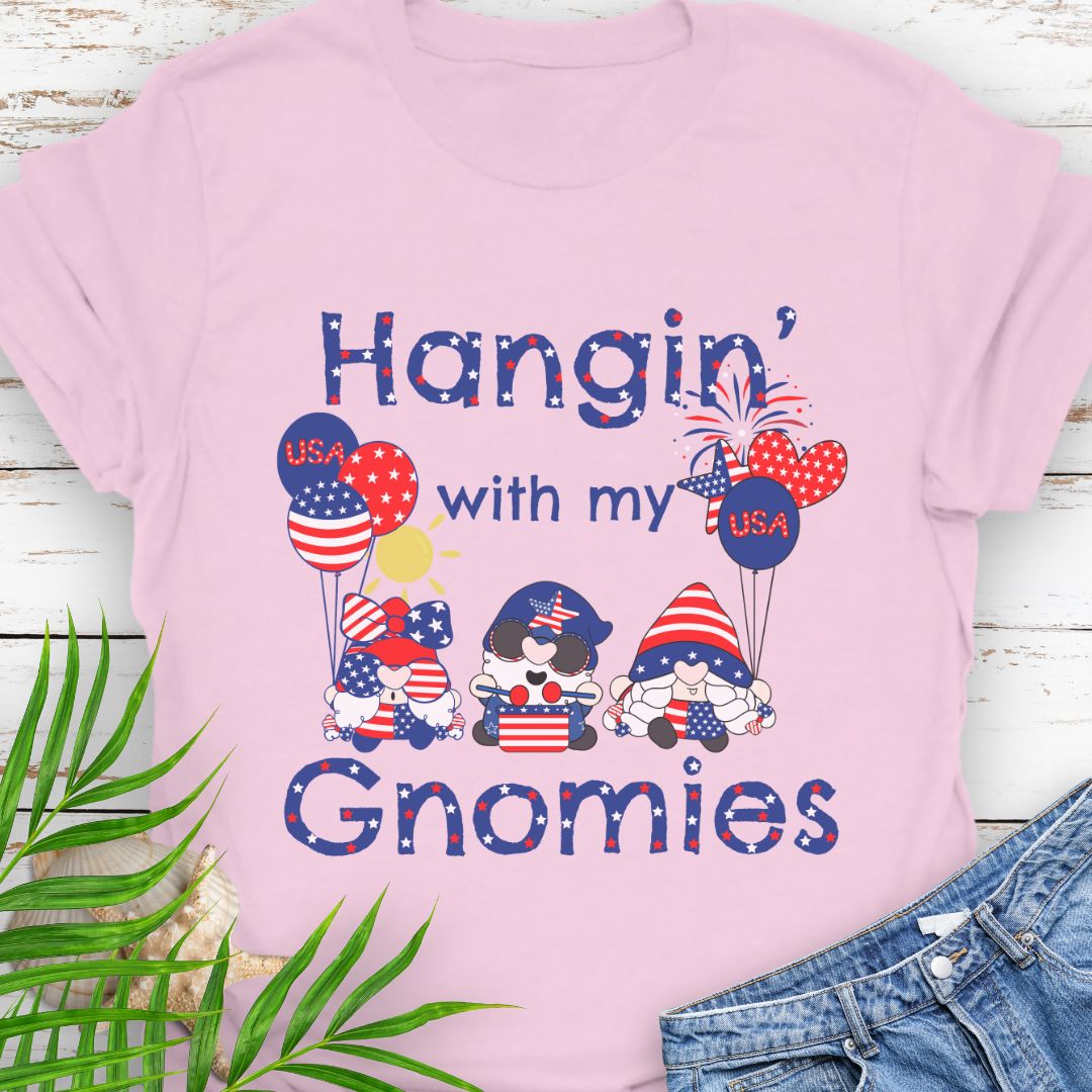 Pink T-shirt with three gnomes in patriotic outfits holding flag balloons with sun and fireworks in the background with the phrase Hangin' with my Gnomies.