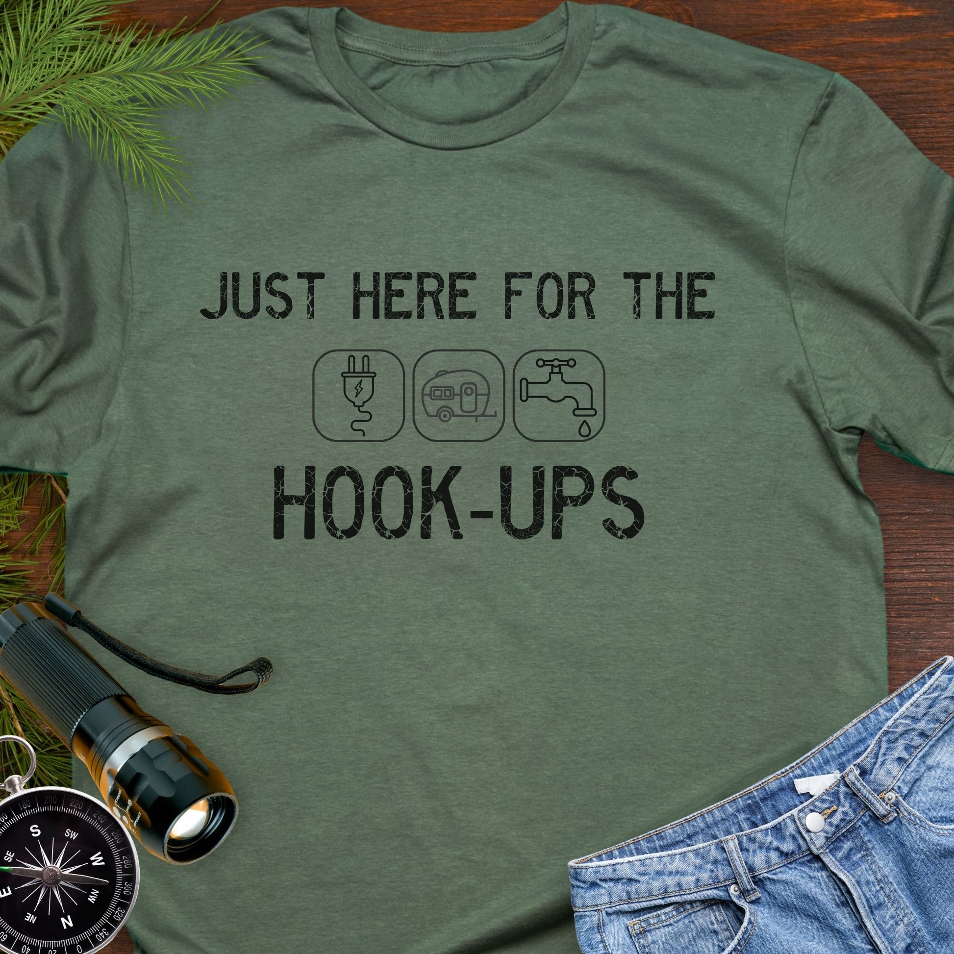 Military Green funny camping t-shirt with ‘Here for the Hook-ups’ text and RV utility icons.