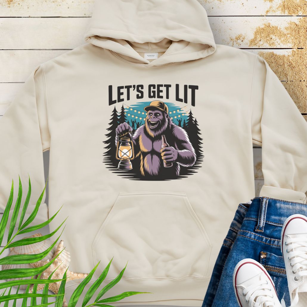 Sand funny Sasquatch camping unisex hoodie with relaxed outdoor party vibe that says Let's Get Lit featuring a sasquatch wearing a ball cap holding a camping lantern and a bottle of beer with the forest in a forest camp scene.