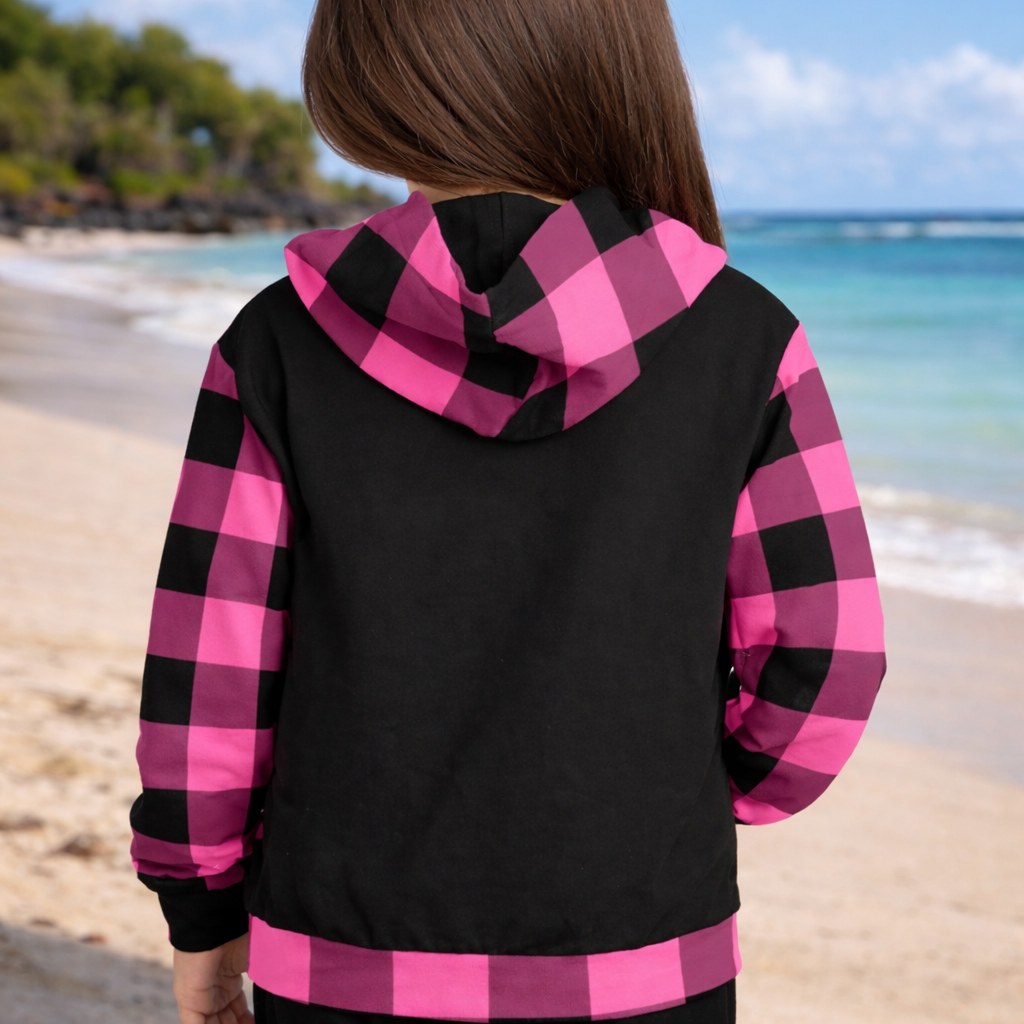 Person wearing a black and pink checkered hoodie on a beach