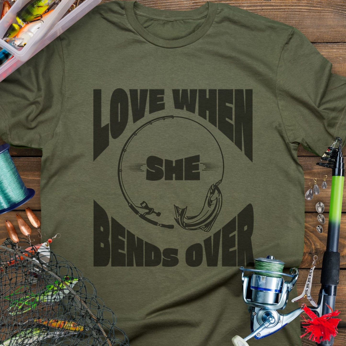 Military Green T-shirt with a fishing pole bending over and the phrase “Love When She Bends Over” – humorous fishing design for anglers.