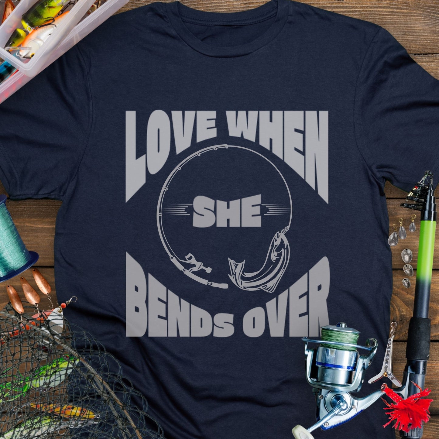 Navy T-shirt with a fishing pole bending over and the phrase “Love When She Bends Over” – humorous fishing design for anglers.