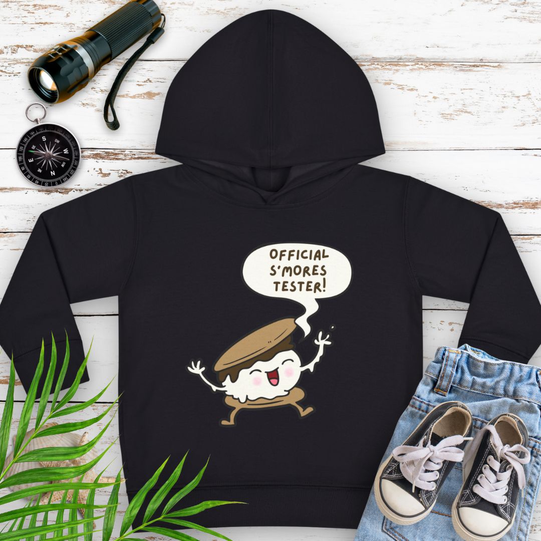 Black cozy toddler hoodie with “Official S’mores Tester” speech bubble and a cartoon s'more – cute outdoor-themed sweatshirt for little campers.