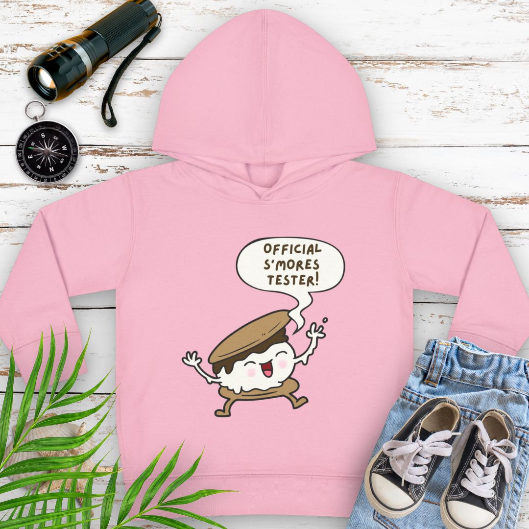 Pink cozy toddler hoodie with “Official S’mores Tester” speech bubble and a cartoon s'more – cute outdoor-themed sweatshirt for little campers.