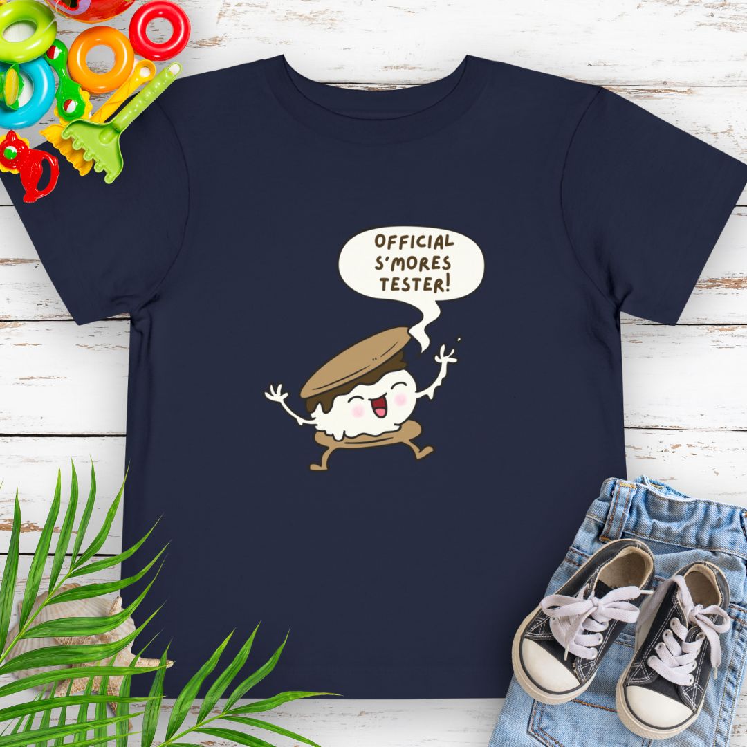 Navy Toddler T-shirt with "Official S'mores Tester" text in speech bubble over a S'more character – perfect for camping and summer fun.