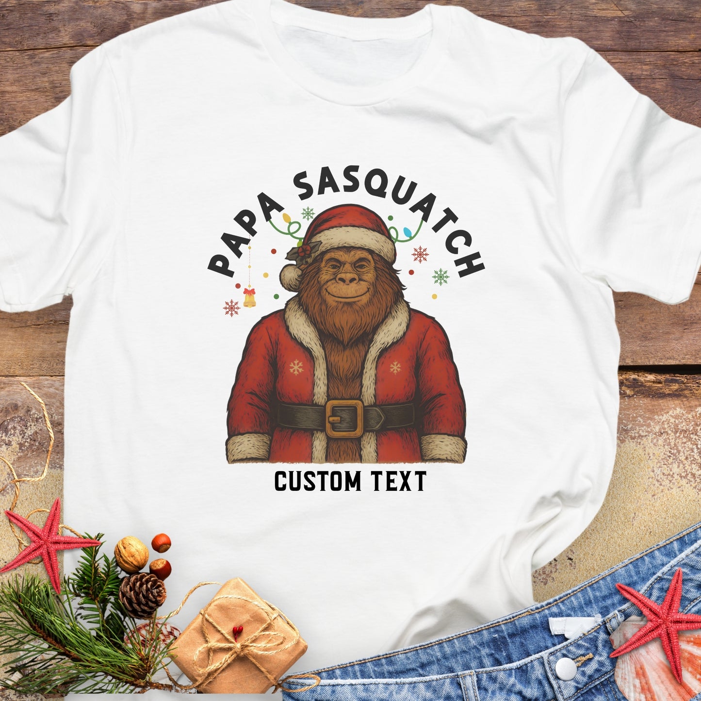 White t-shirt with a graphic of a Sasquatch in a Santa outfit and 'Papa Sasquatch' with custom text.