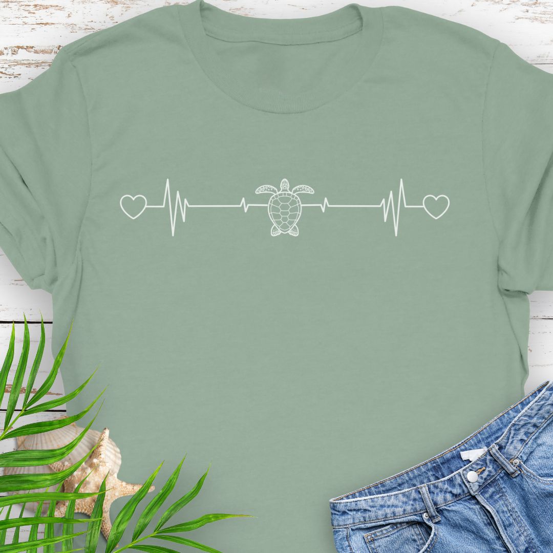 Sage T-shirt with ocean heartbeat design with sea turtle in center symbolizing love for sea turtles.