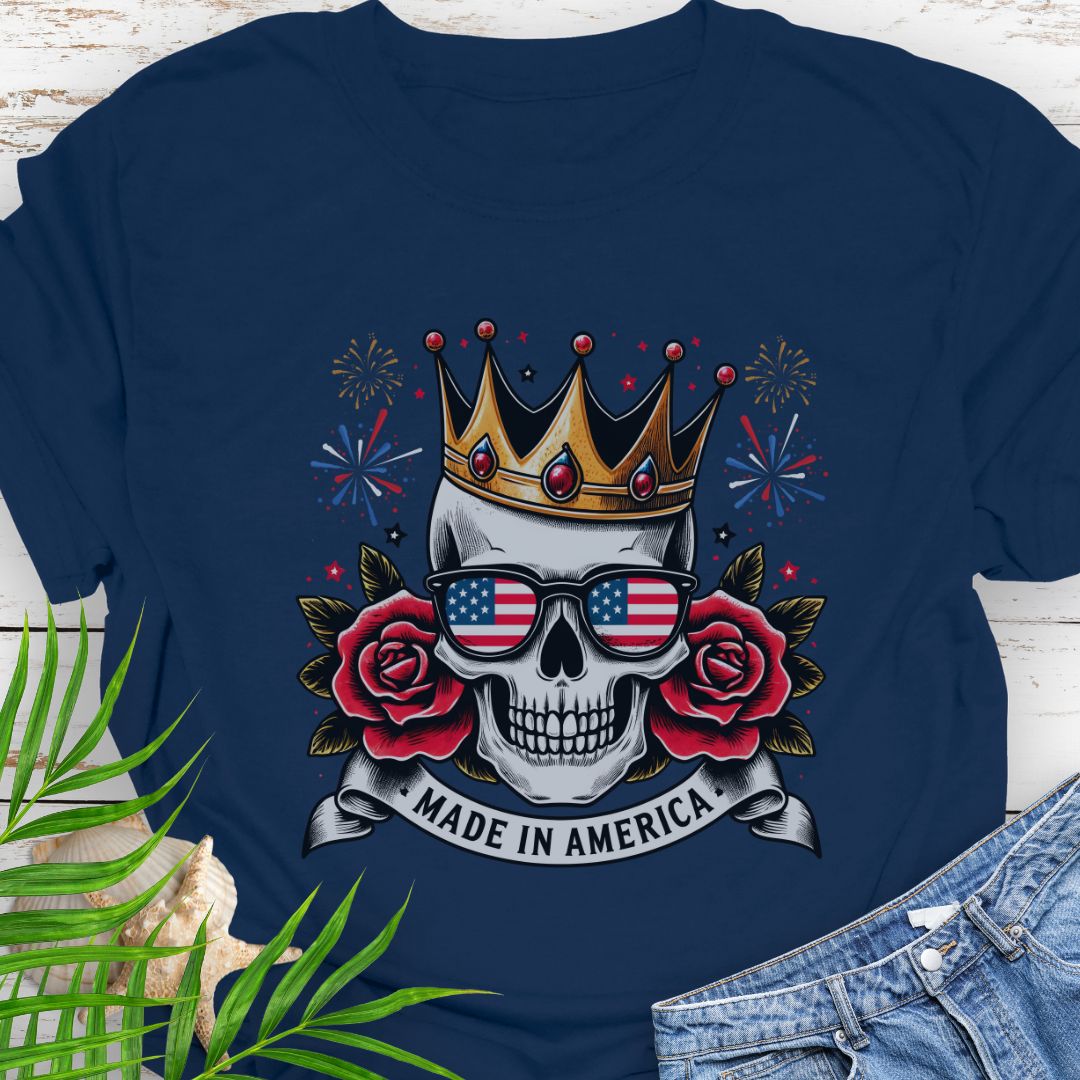 Navy blue T-shirt with a skull wearing a crown and American flag sunglasses, surrounded by red roses with fireworks in the background and a "Made in America" banner.