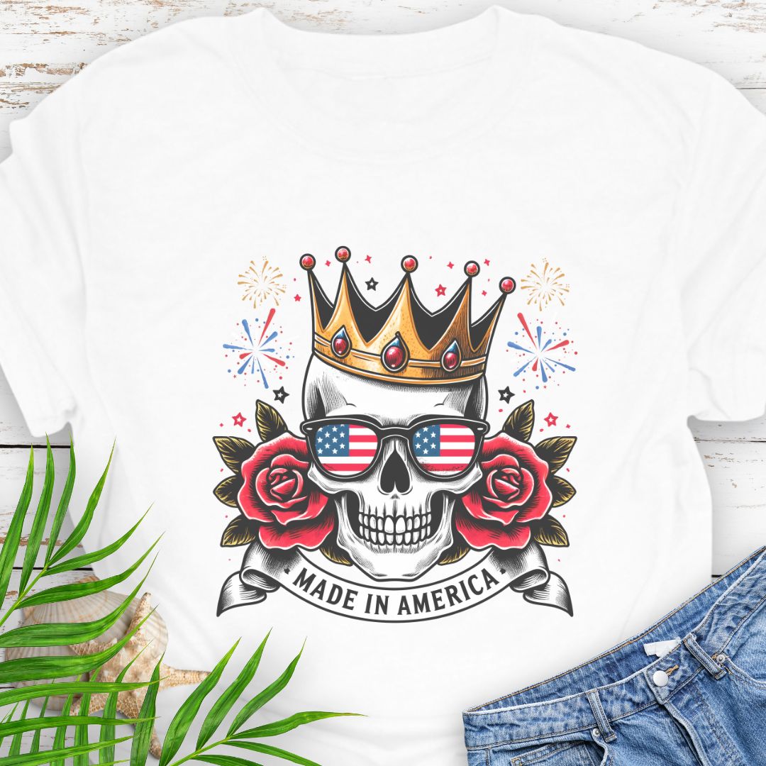 White T-shirt with a skull wearing a crown and American flag sunglasses, surrounded by red roses with fireworks in the background and a "Made in America" banner.